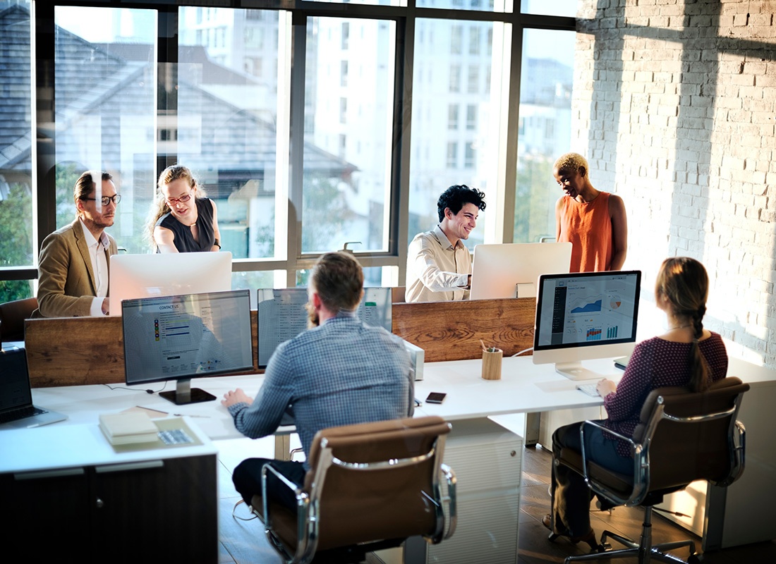 Business Insurance - View of a Diverse Team Working on Computers in a Modern Bright Office with Large Windows
