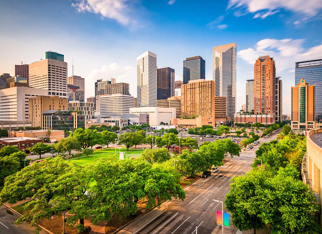 Houston, TX - View of Green Trees Surrounding a Park in Downtown Houston Texas with Modern Commercial Buildings Against a Blue Sky at Sunset