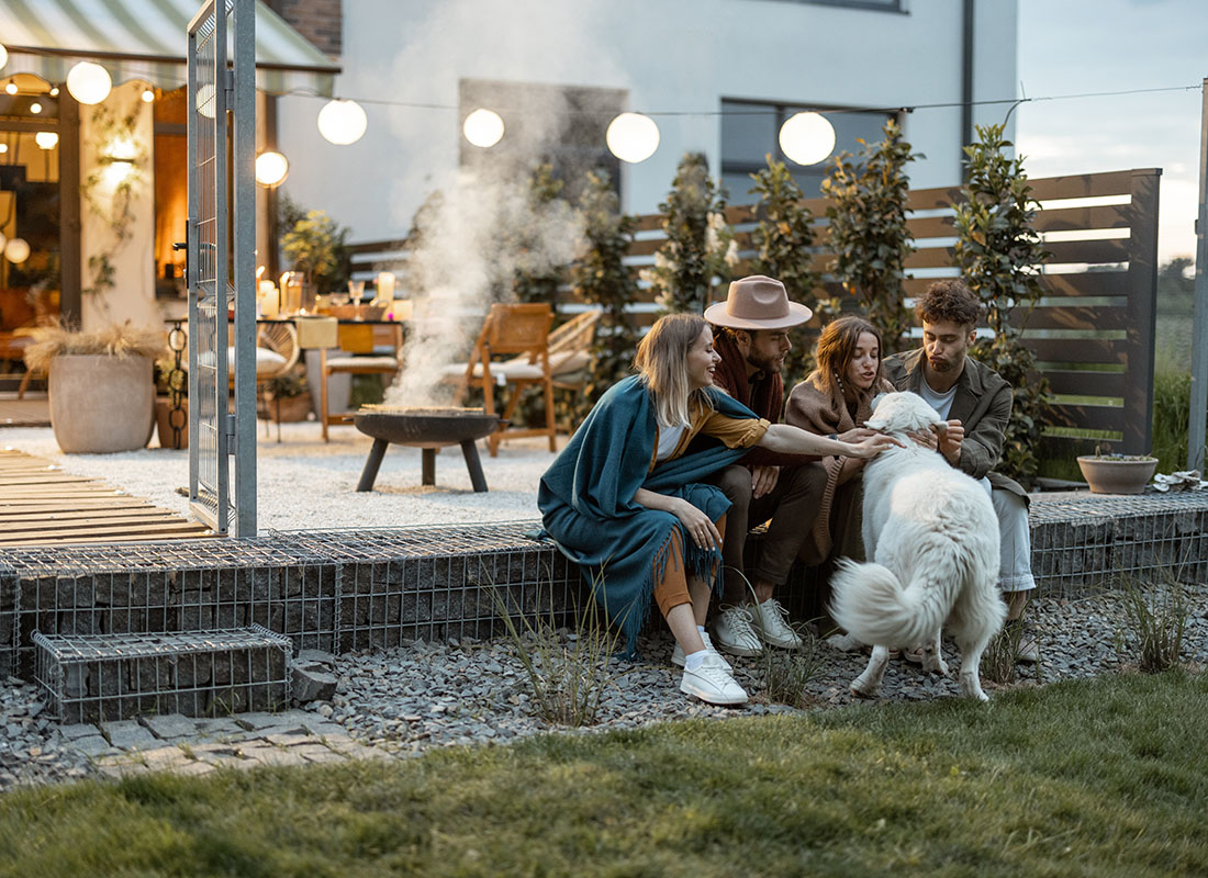 Insurance Solutions - View of a Small Group of Friends Petting a Dog Having Fun Spending Time Together Sitting Outside on the Patio During the Evening